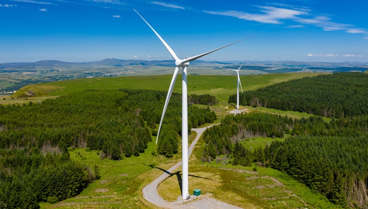 turbines at a large onshore windfarm on a green hillside (Pen y Cymoedd, Wales)
